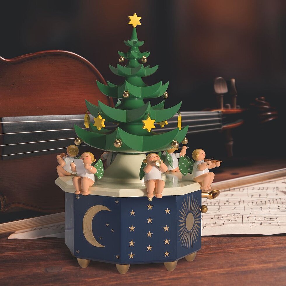 Handgefertigte Spieldose von Wendt & Kühn mit Weihnachtsbaum und Engelmusikanten vor einer Geige und Notenblatt als festliche Weihnachtsdekoration.