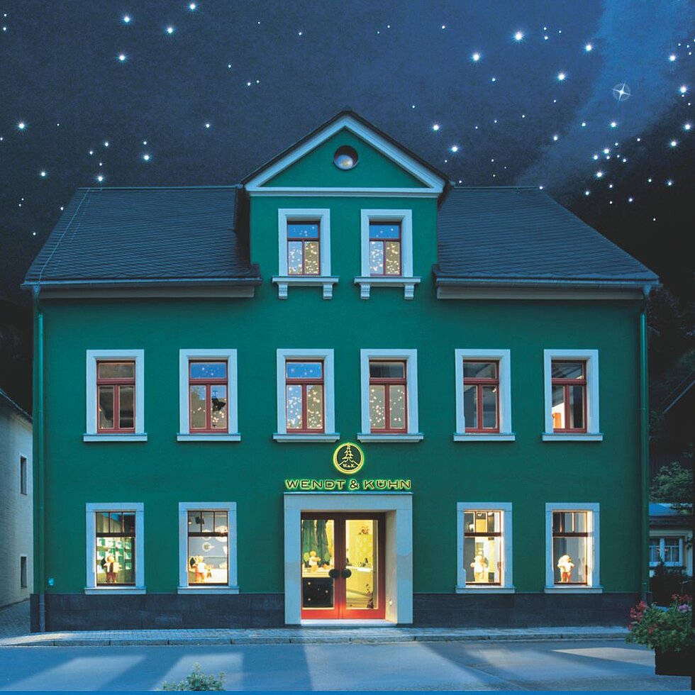 Grünes Haus der Figurenwelt in Seiffen unter nächtlichem Sternenhimmel