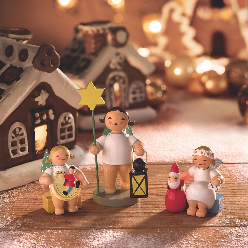 Handgefertigte Engelfiguren von Wendt & Kühn vor einem winterlichen Weihnachtsdorf mit beleuchteten Häusern und weihnachtlicher Dekoration