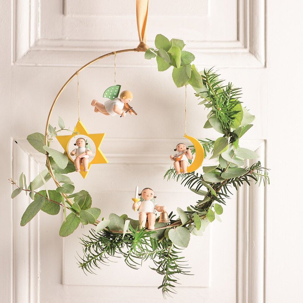 Weihnachtskranz mit handgefertigten Engelanhängern von Wendt & Kühn, darunter Engel im Stern, Engel im Mond und musizierende Engel als festliche Tür- oder Wanddekoration.