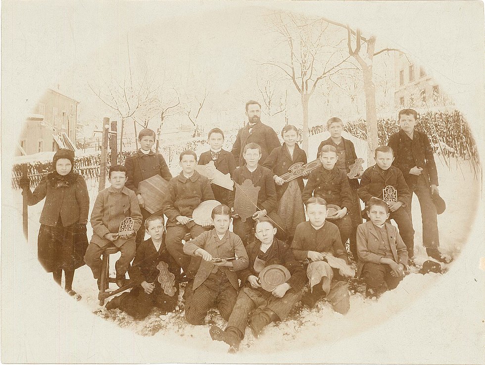 Historische Aufnahme. Klassenfoto aus der Gewerbeschule. Grete Wendt als einziges Mädchen in der Klasse. Aufnahme im Winter, die Kinder sind in Mäntel und Mützen gekleidet. Es liegt Schnee.