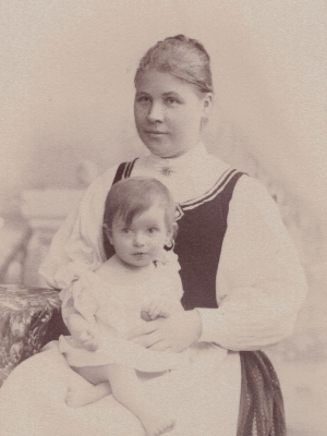 Historische Schwarz-Weiß-Fotografie. Olly als Baby auf dem Schoß ihrer Mutter.