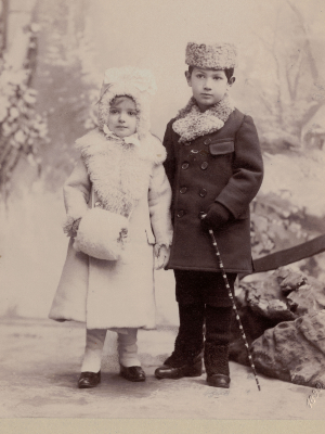 Historische Schwarz-Weiß-Fotografie. Olly und Herbert als Kinder. Olly trägt einen hellen Wintermantel, Herbert einen dunklen.