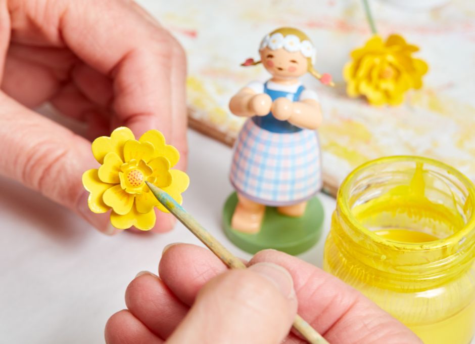 Bemalung einer handgefertigten Blüte aus Holz in gelber Farbe in den Werkstätten von Wendt & Kühn