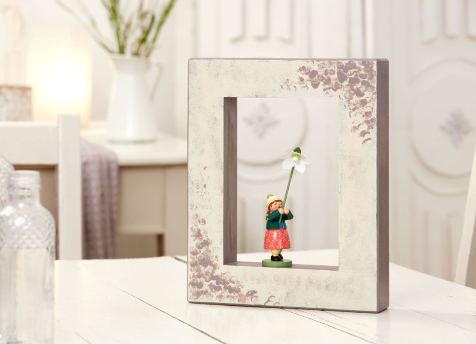 Hellbemalter Holzrahmen mit Figur mit Blüte in Wohnzimmer