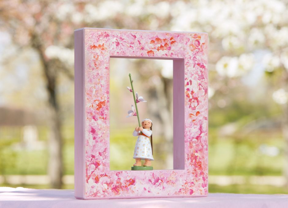Rosa Holzrahmen mit Figur mit Kirschblüte vor blühendem Kirschbaum