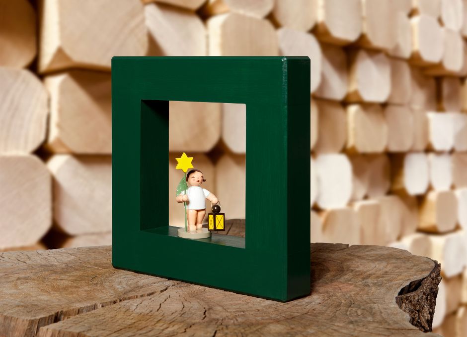 Grüner Holzrahmen mit Engelsfigur vor Holzstapel